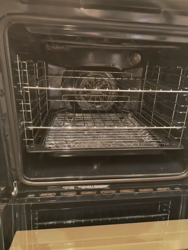Clean stainless steel oven fitted in a white kitchen after professional cleaning